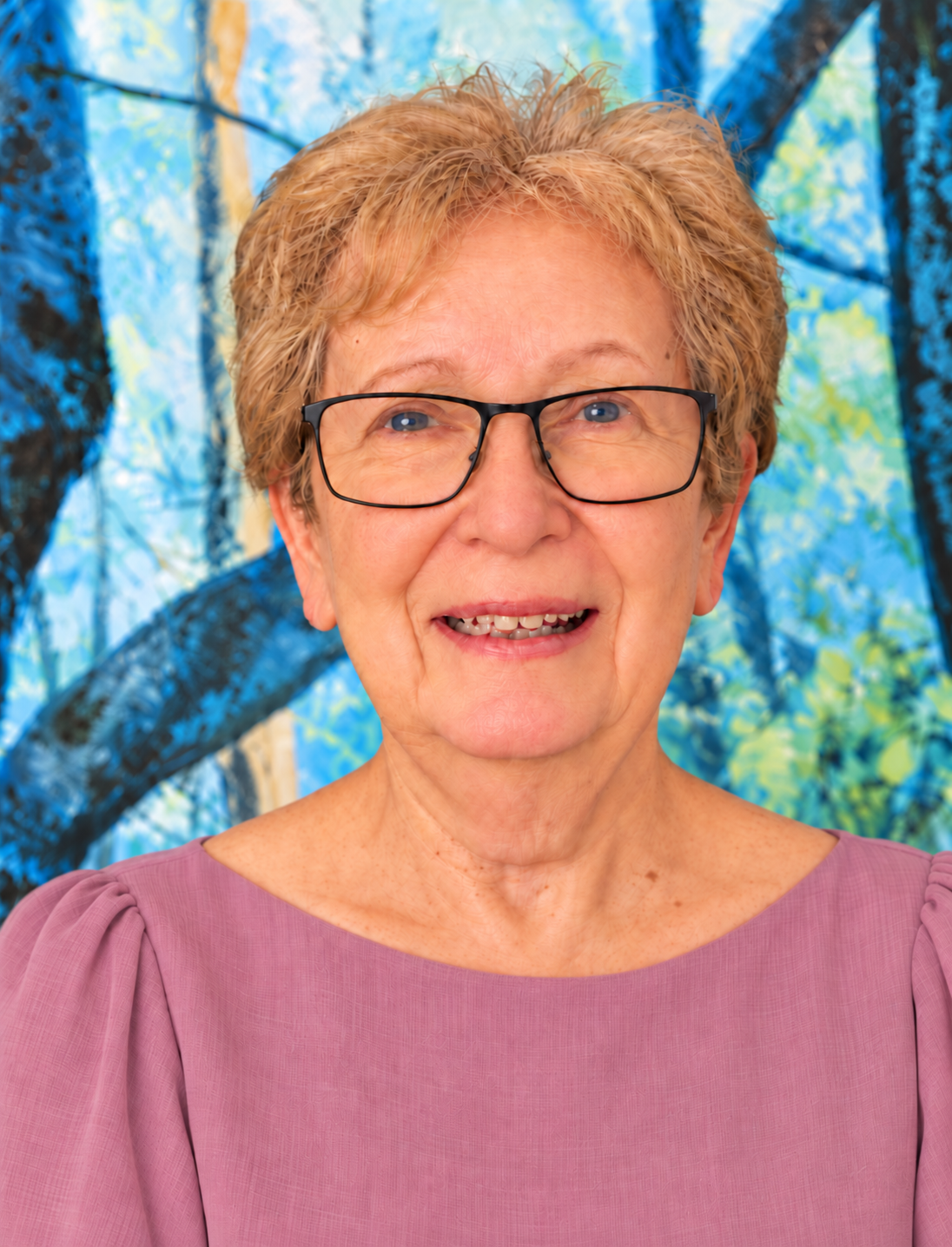Judith Weinstein in a mauve blouse, with a blue-green painting behind her