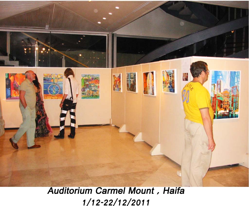 A visitor in a yellow shirt stands beside city paintings on display panels, while other visitors walk through the exhibition.